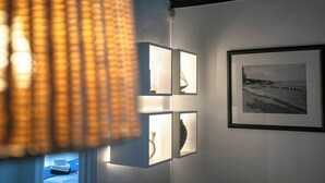 A room with a bed, a wall-mounted light fixture, and a framed photograph. - GuestReady OceanFront Casa do Mirante (Ponta Delgada)