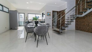 A modern kitchen with a dining area, a staircase, and a view of the city. - GuestReady - Sunset House (Relva)