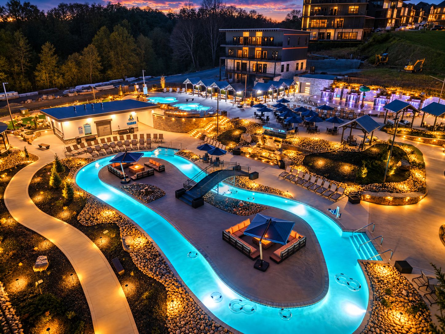 Un complejo turístico con varias piscinas, zonas de estar al aire libre y un edificio bien iluminado.