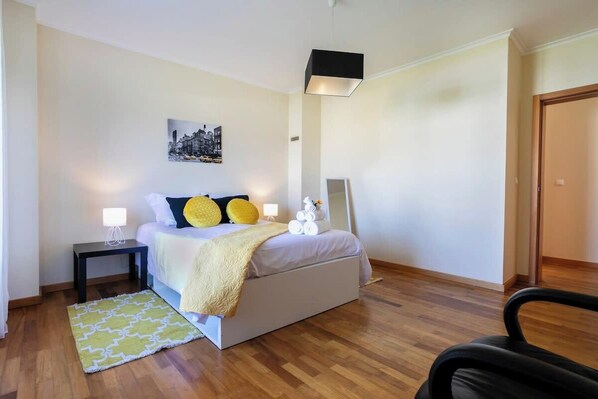A bedroom with a bed, bedside tables, a lamp, a chair, and a rug. - GuestReady - Casa do Parque (Ponta Delgada)