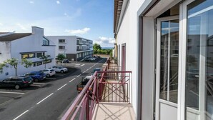 A modern building with a balcony overlooking a street with parked cars. - GuestReady - Casa do Parque (Ponta Delgada)