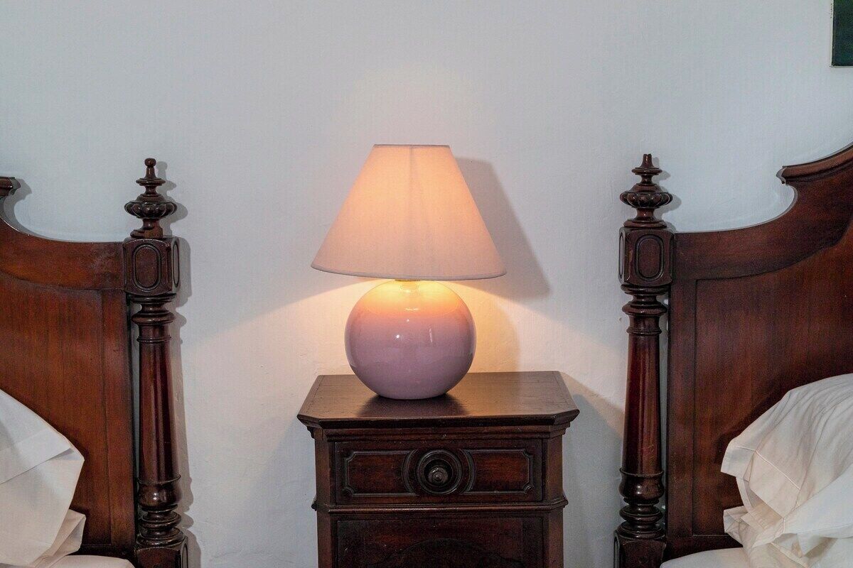 Ein Nachttisch aus Holz mit Lampe zwischen zwei Betten mit Holz-Kopfteilen.