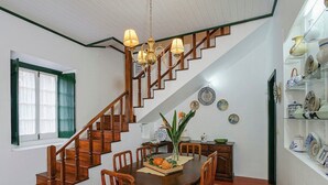 A dining area with a wooden staircase, a chandelier, and a wall of decorative plates.