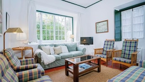 A living room with a sofa, armchairs, a coffee table, and a television.