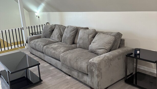 Una sala de estar moderna con un sofá gris a rayas, dos mesas auxiliares negras y una mesa de centro de cristal.