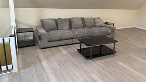Una sala de estar con un sofá gris, dos mesitas auxiliares negras y una mesa de centro oscura.