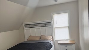 Un dormitorio con cama, mesita de noche y ventana.