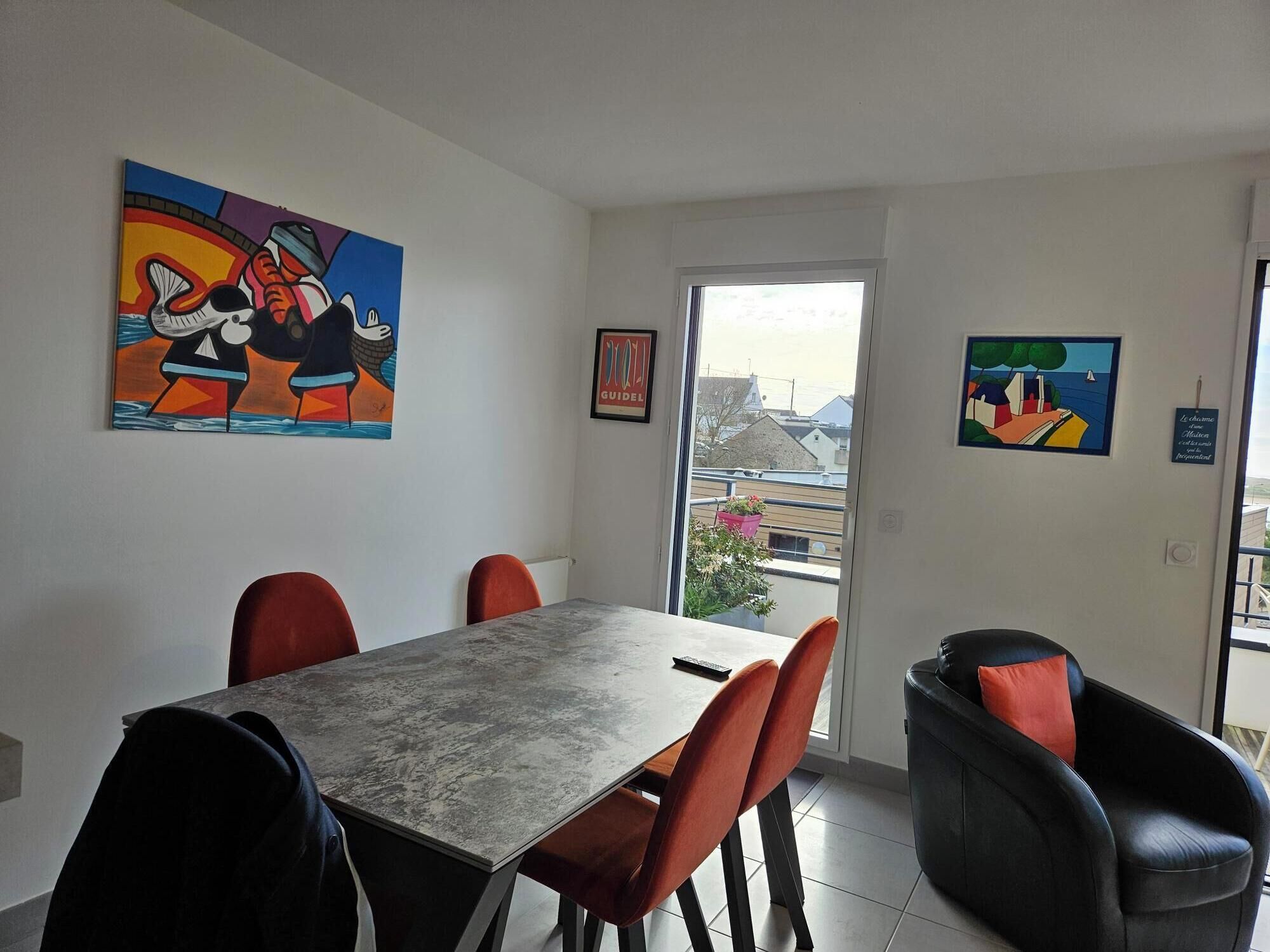 Zona pranzo con tavolo e sedie, un quadro appeso al muro e vista attraverso una porta vetrata.