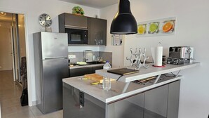 Eine moderne Küche mit einer zentralen Kochinsel, Edelstahlgeräten und einer Pendelleuchte.