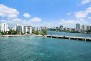 A coastal cityscape with a bridge over water, modern buildings, and a clear sky.
