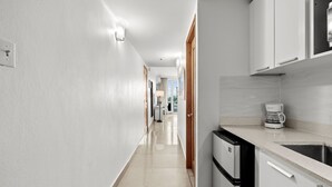 A modern kitchen with white cabinetry, a stainless steel sink, and a coffee maker.