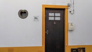 Une porte ornée d’une fenêtre en forme de cœur, une boîte aux lettres et une boîte électrique fixée au mur.