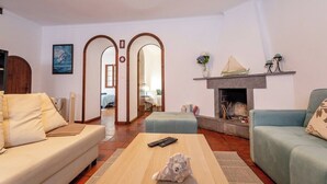 Un salon avec un canapé, une table basse et une cheminée. Il y a une télécommande sur la table.