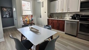 A modern kitchen with stainless steel appliances, white cabinets, and a dining area with a white table and two chairs.
