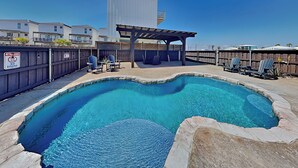 A swimming pool with a curved design, surrounded by stone walls and a wooden deck.