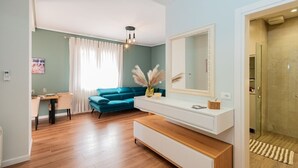 A modern living room with a teal sofa, a wooden coffee table, a white console table, and a large mirror. - Lovely 2-bedroom apartment with sea view in Durrës (Durrës)