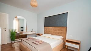 A modern bedroom with a large bed, bedside tables, a mirror, and a hanging light fixture. - Lovely 2-bedroom apartment with sea view in Durrës (Durrës)
