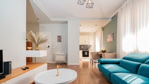 A modern living room with a blue sofa, a round white table, and a TV on a wooden cabinet. - Lovely 2-bedroom apartment with sea view in Durrës (Durrës)