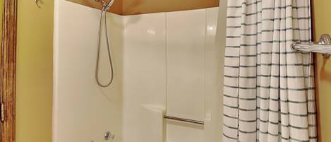 A bathroom with a bathtub, shower, and a striped shower curtain.