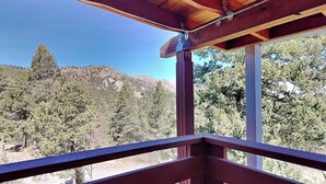 A wooden balcony with a view of a forested hillside. - Wild Horse Haven by Ruidoso Vacation Rentals (Alto)