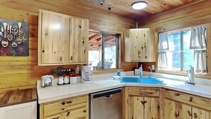 A kitchen with wooden cabinets, a dishwasher, a coffee maker, and a sink. - Wild Horse Haven by Ruidoso Vacation Rentals (Alto)