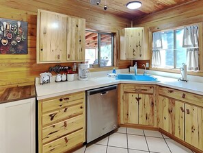 A kitchen with wooden cabinets, a dishwasher, a coffee maker, and a sink. - Wild Horse Haven by Ruidoso Vacation Rentals (Alto)