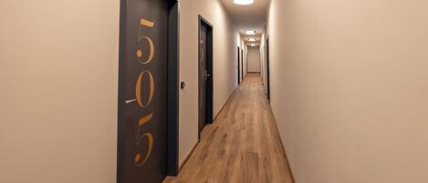 A hallway with wooden flooring and doors marked with numbers.