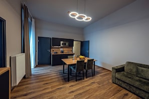 A modern kitchen with a microwave, a dining table with chairs, and a green sofa. - Residency NO7 (Berlin)