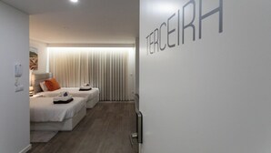 Een moderne hotelkamer met twee bedden, een groot raam met zonwering en een radiator aan de muur.