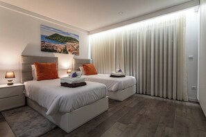 Ein modernes Hotelzimmer mit zwei Betten, einem großen Fenster mit leichtem Vorhang, einem Gemälde an der Wand und Holzboden.