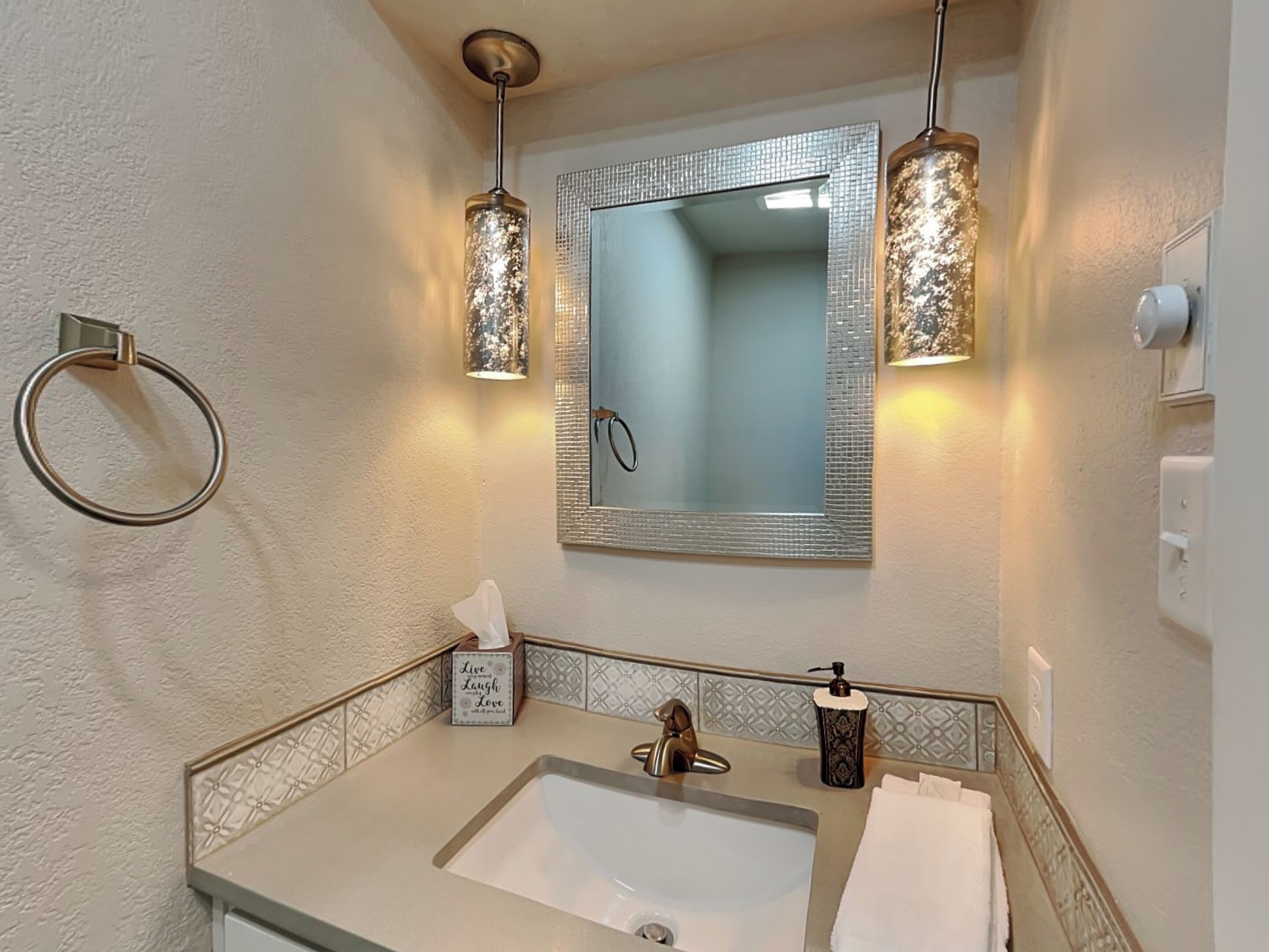 A bathroom with a sink, mirror, towel rack, and two wall-mounted lights.