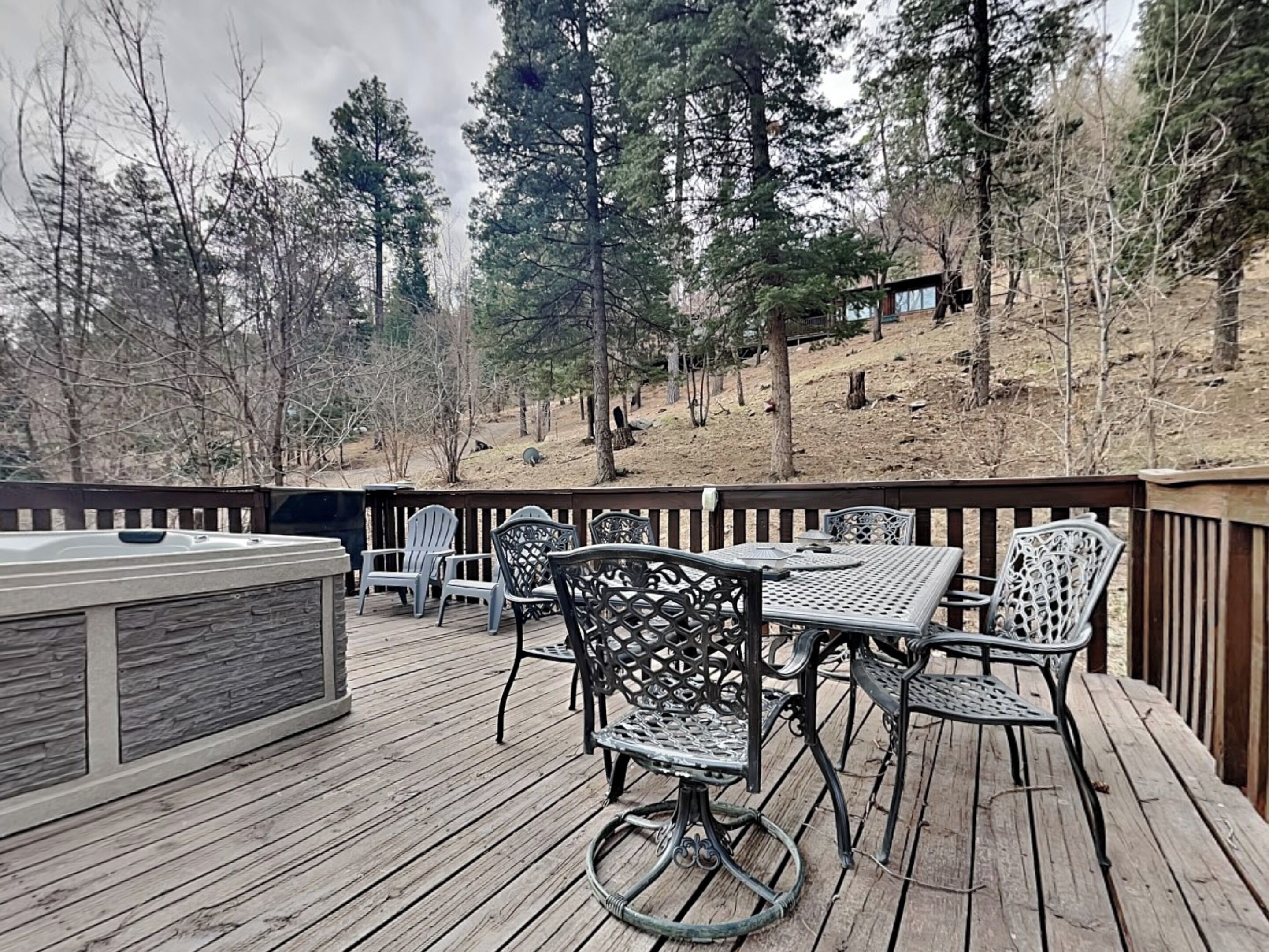 Une terrasse en bois aménagée avec du mobilier d’extérieur, notamment une table et des chaises, ainsi qu’un jacuzzi.