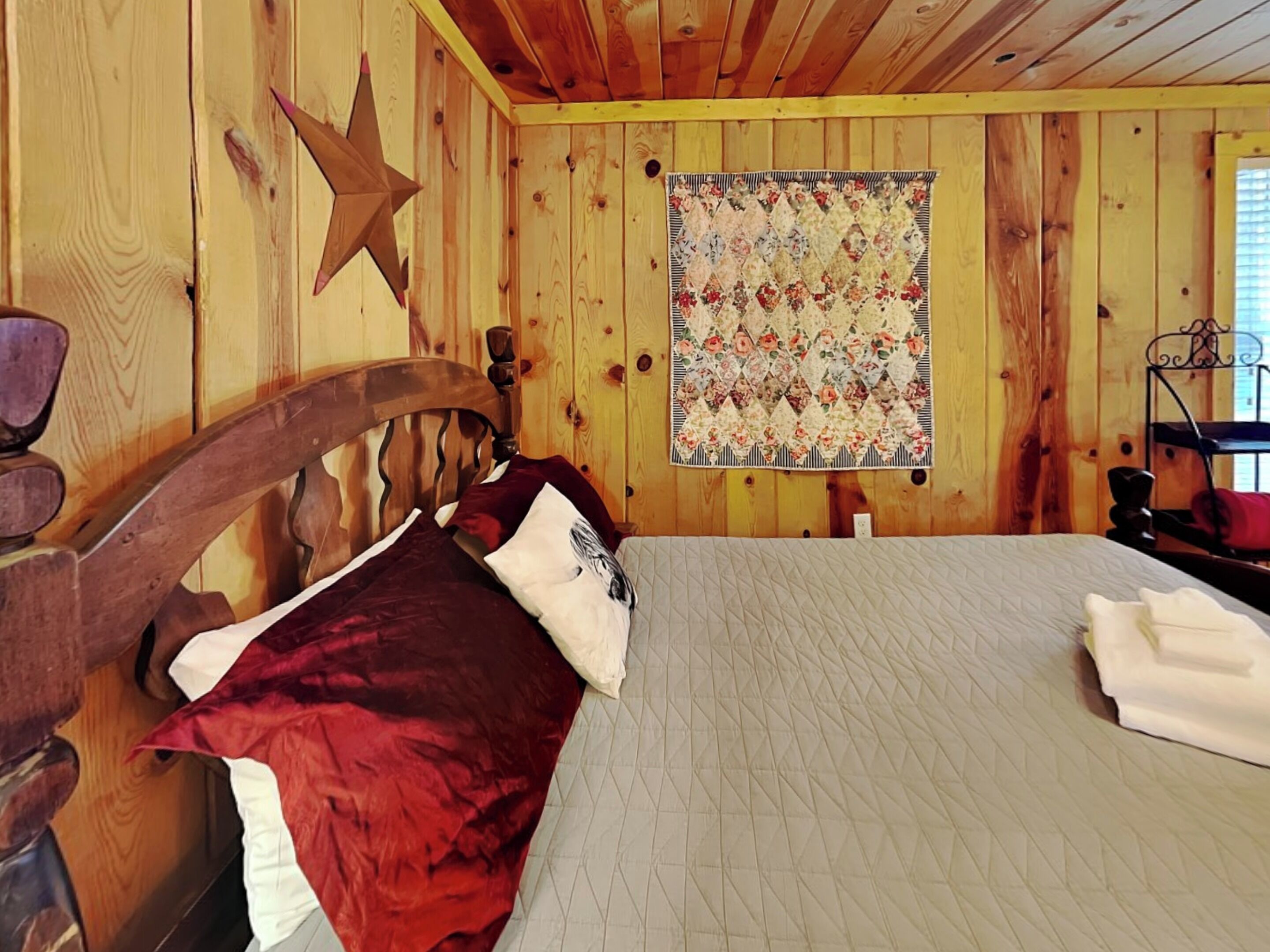 A wooden cabin room with a bed, a quilted wall hanging, and a star decoration.