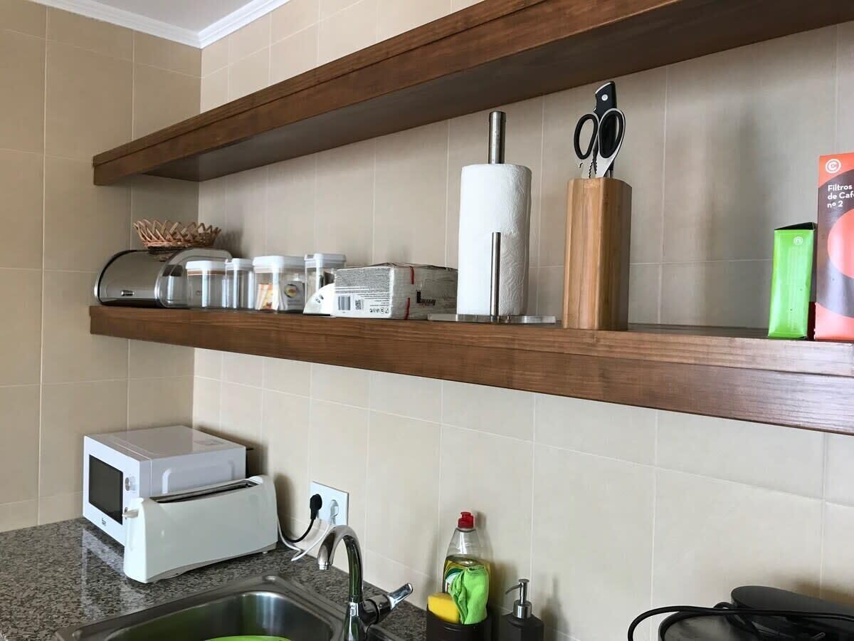 Une cuisine équipée d’un four à micro-ondes, d’un grille-pain et d’un évier. Des étagères au-dessus du plan de travail servent à ranger divers ustensiles de cuisine.