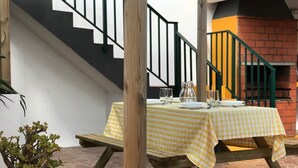 An outdoor patio with a table set for two, a staircase, and a brick oven.