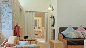 A cozy living room with a wooden sofa, a small wooden table, and a cushioned bench. A red fire extinguisher is mounted on the wall.