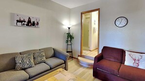 A living room with two sofas, a coffee table, a clock, and a framed picture on the wall. - Pinon Park A15 by Ruidoso Vacation Rentals (Ruidoso)