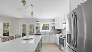 A modern kitchen with white cabinetry, stainless steel appliances, and a large island.