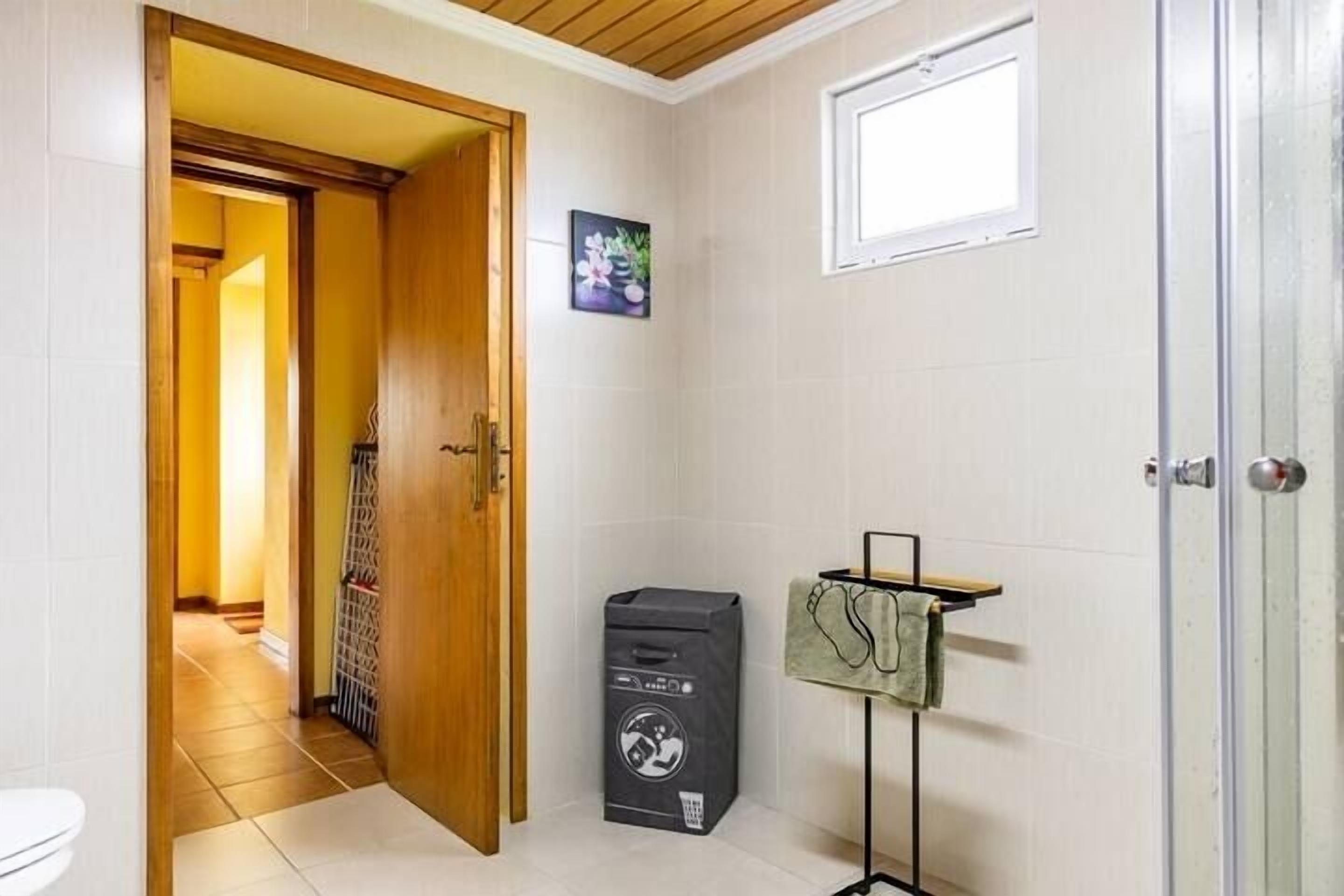 Casa de banho com sanita, um cesto de lixo, porta-toalhas e janela.