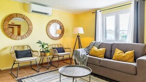 Ett vardagsrum med en soffa, två fåtöljer, en lampa och två speglar som hänger på väggen.