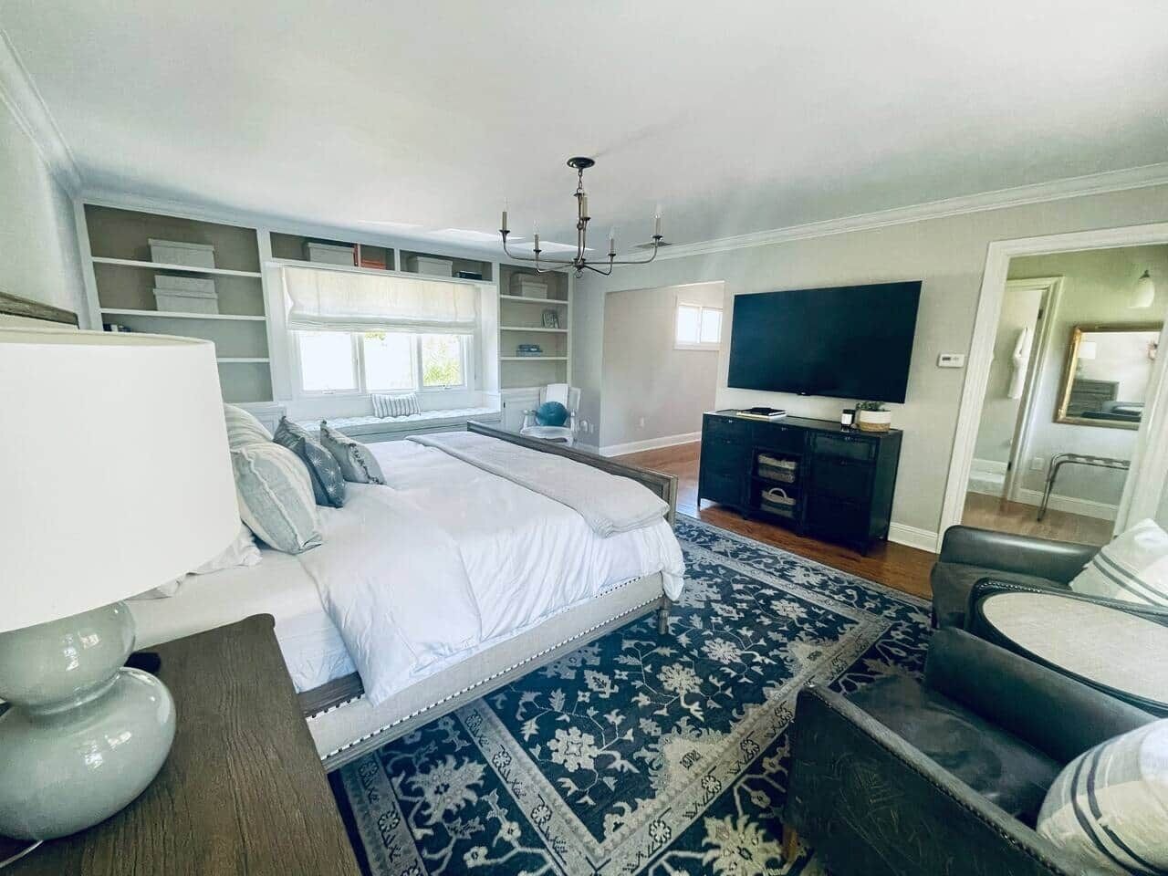 Ein modernes Schlafzimmer mit einem großen Bett, einem Fernseher, einem Schreibtisch und integrierten Regalen.