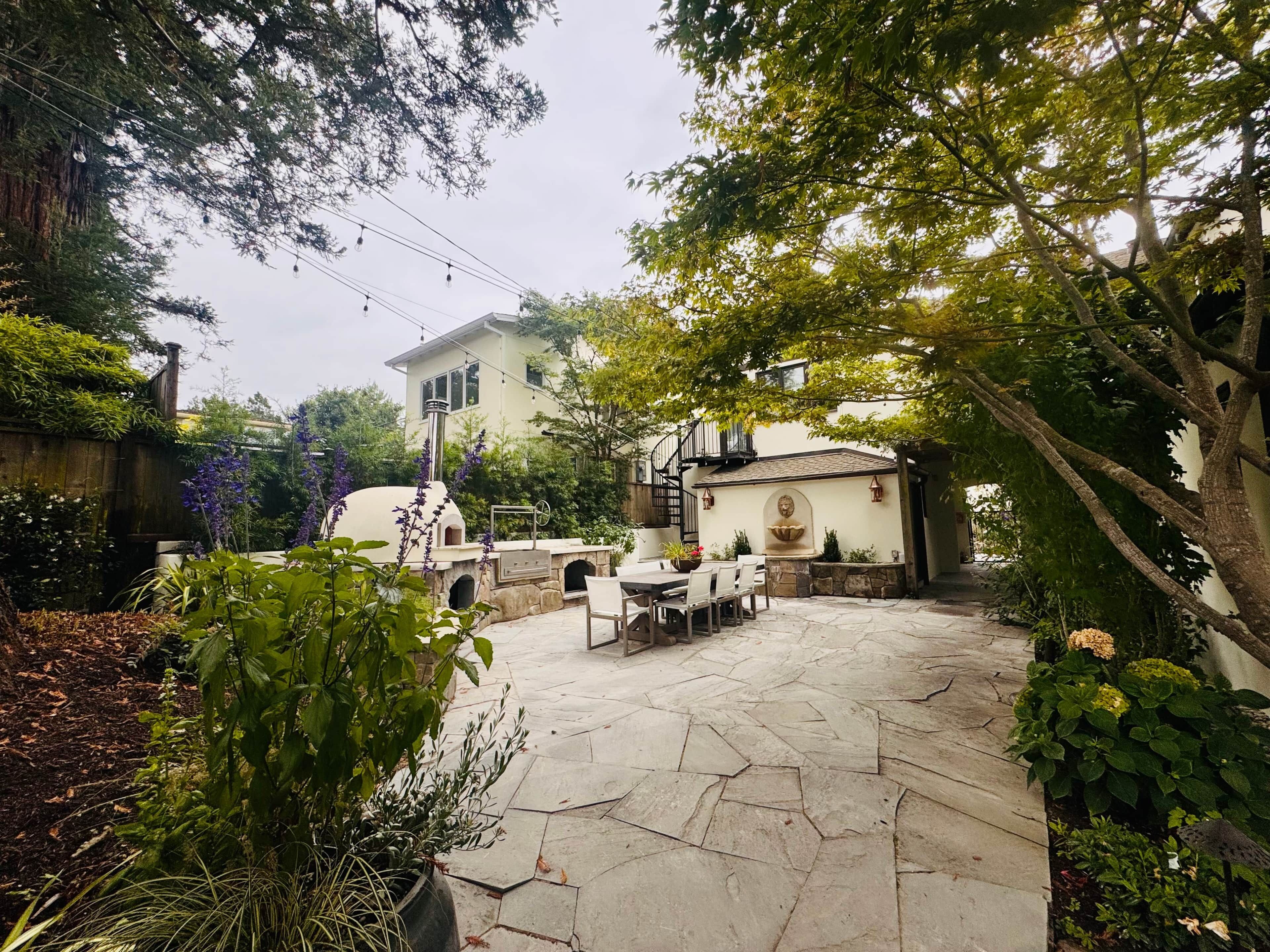 Ein Patio mit Steinboden, Sitzgelegenheiten im Freien und einem Haus im Hintergrund.