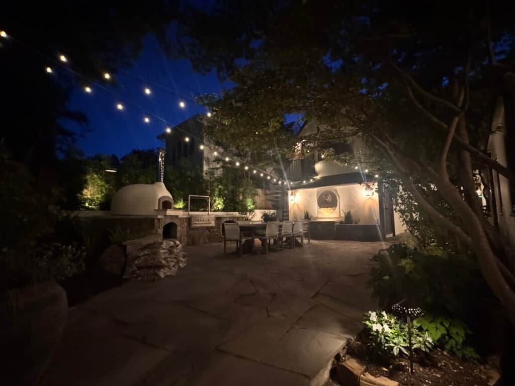 An outdoor patio area with stone flooring, a seating arrangement, and string lights.