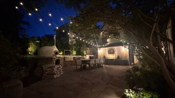 An outdoor patio area with stone flooring, a seating arrangement, and string lights.