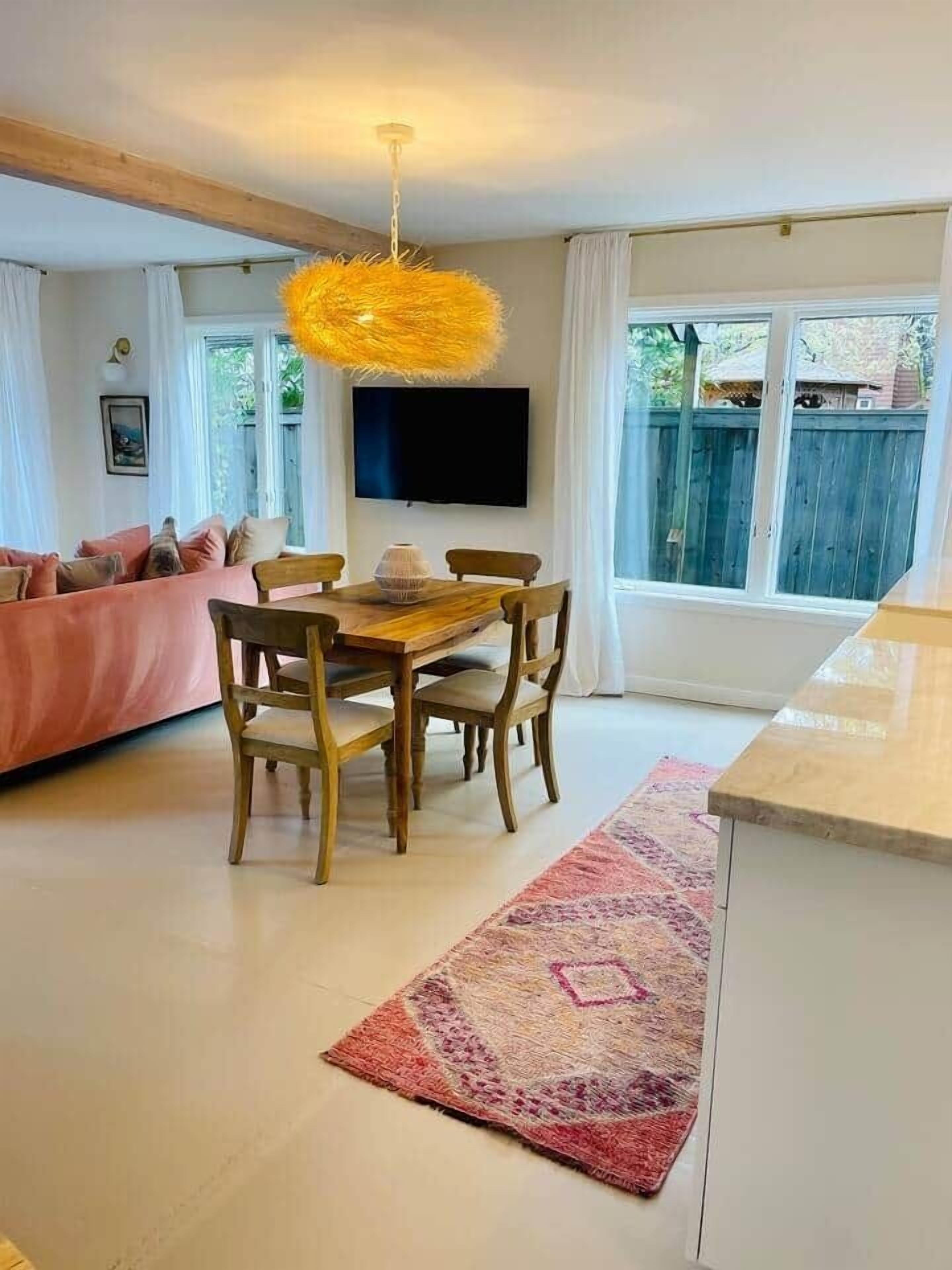 A modern living room with a wooden dining table, a sofa, and a TV.
