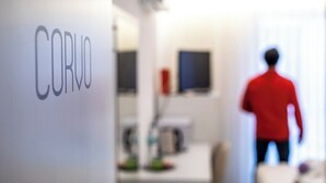 Un couloir avec une pancarte indiquant « CORVO » et une personne portant une veste rouge qui s’éloigne.