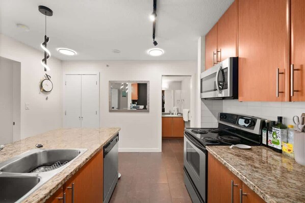 A modern kitchen with granite countertops, stainless steel appliances, and wooden cabinets.