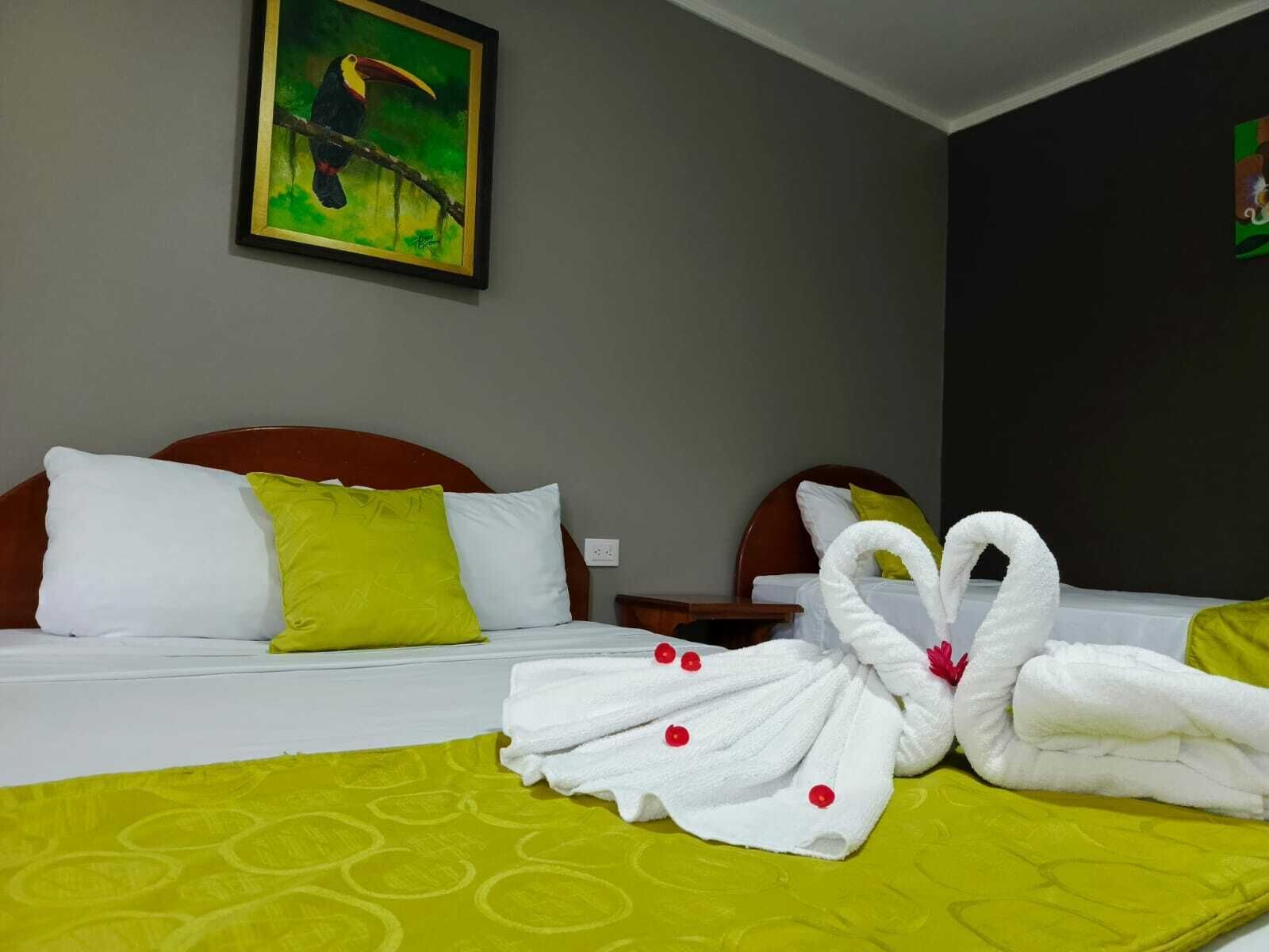 A hotel room with a bed, pillows, a nightstand, and a painting on the wall.