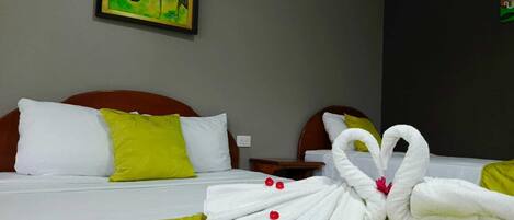 A hotel room with a bed, pillows, a nightstand, and a painting on the wall.