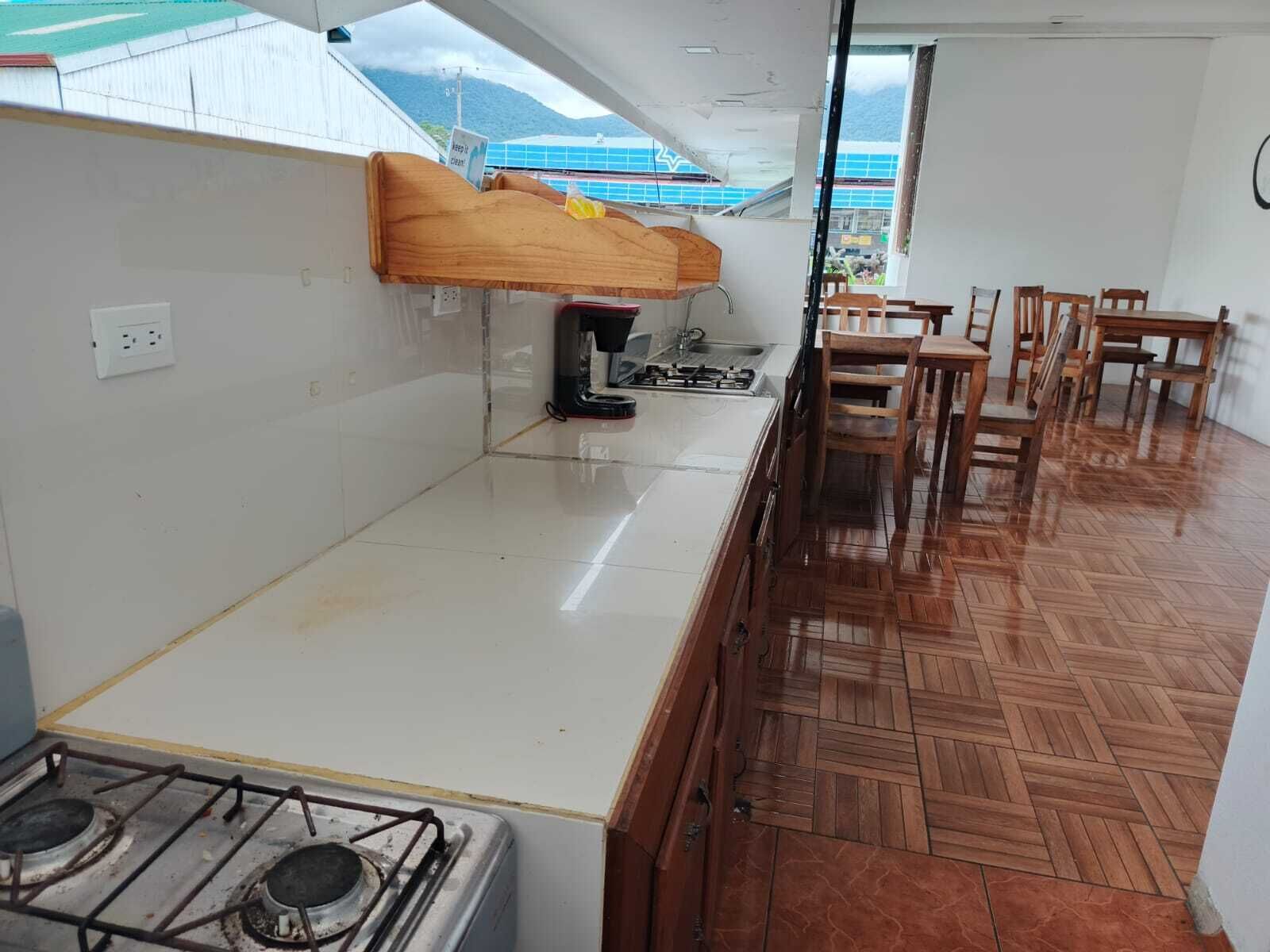 A kitchen with a gas stove, wooden cabinets, and a dining area with wooden chairs.